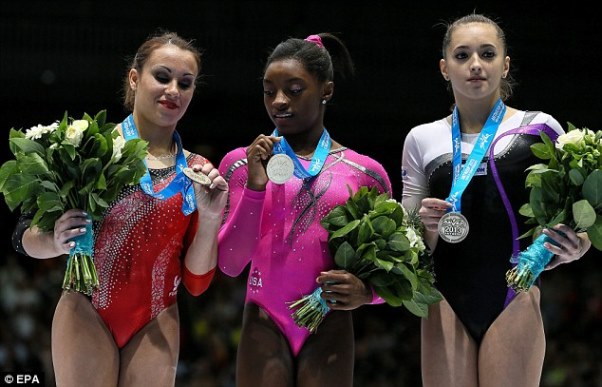 On her way to glory: Simone Biles, centre, picks up gold in the floor exercise competition on her way to becoming the first black world champion. Photo courtesy DailyMail