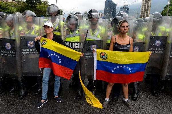 Anti-Maduro demonstrators hold national flags during a protest in front of members of the National Police in Caracas on May 11, 2016. Photo courtesy (AFP Photo/Juan Barreto and www.vidostream.com